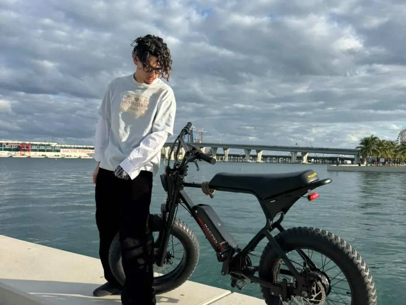 Macfox X1S class 2 e-bike parked by the waterfront with a rider standing beside it