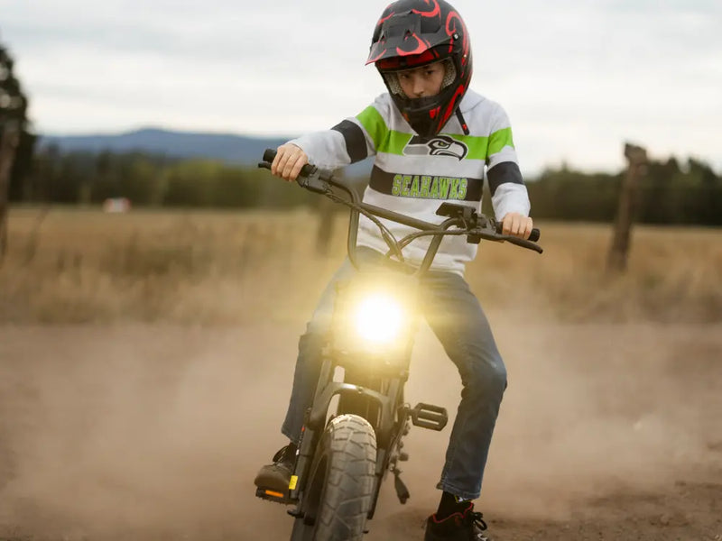 Rider on a Macfox M16 electric bike riding on a dirt road with headlight on