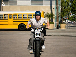 A man rides a Macfox X7 electric bicycle, preparing to accelerate.