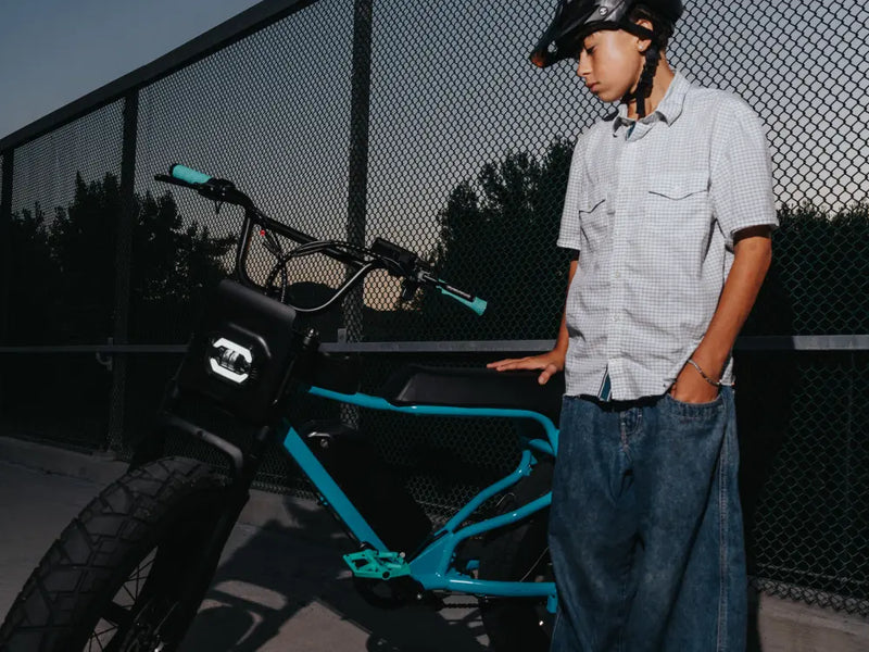 student rider standing beside a Macfox X7 ebike near a fenced court