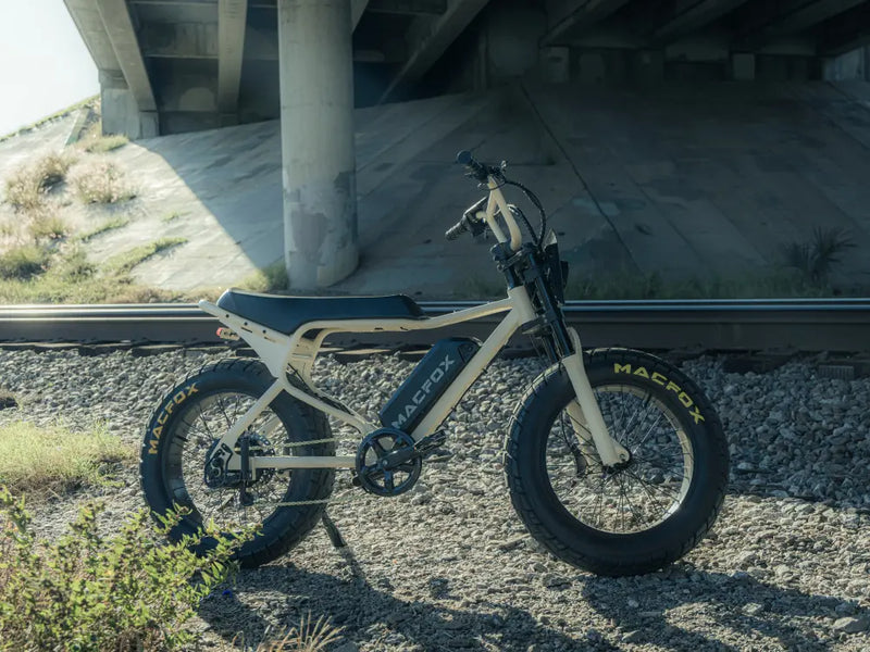 Macfox X7 fat-tire electric bike parked under a bridge on a gravel trail