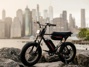 Macfox X1S electric bike parked on rocks with a city skyline in the background