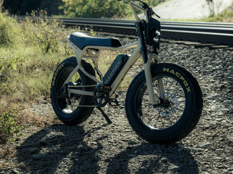Macfox X7 electric bike parked on gravel near grass and trees in an outdoor setting