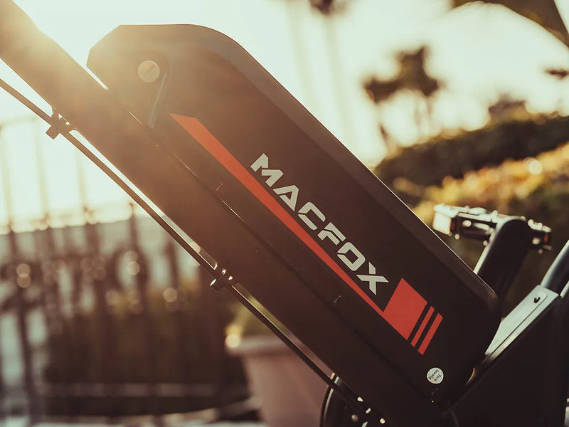 Close-up of a Macfox electric bike battery pack with logo in warm sunset lighting