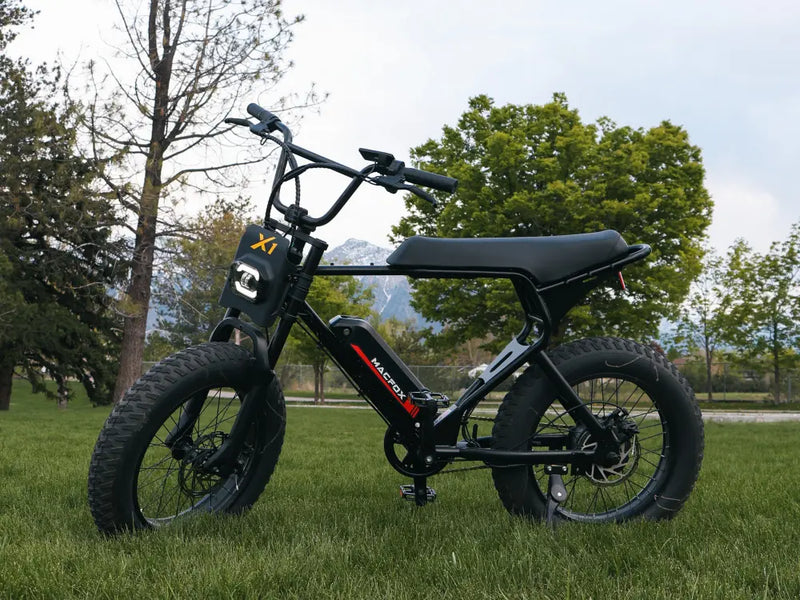 Macfox X1S commuter eBike parked on a grassy field with trees in the background