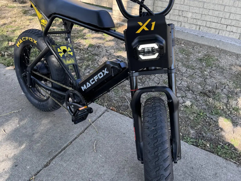Close-up of the fat tire and frame on a Macfox X1S commuter e-bike parked outdoors