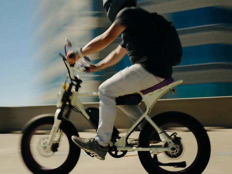 Rider accelerating on a Macfox X1S × Bs.Zay eBike past a modern building