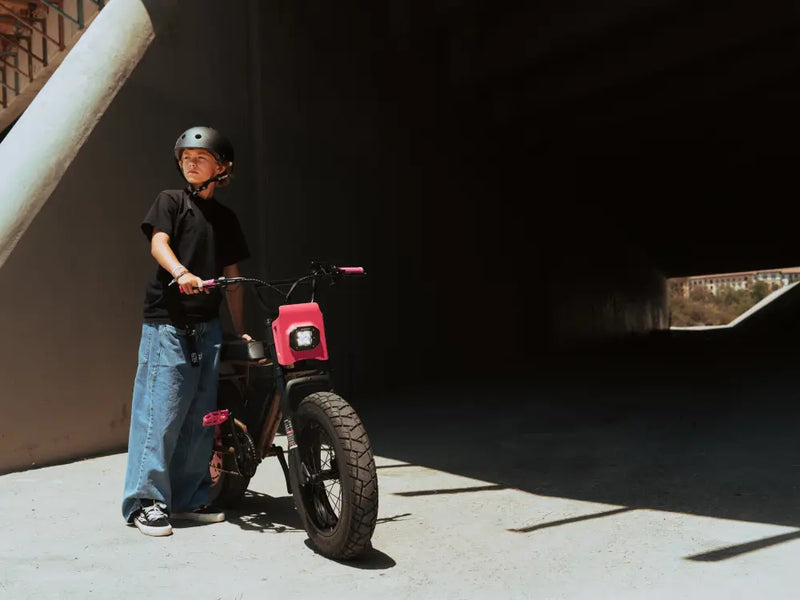 younger rider standing with a Macfox X7 electric bike under a concrete structure