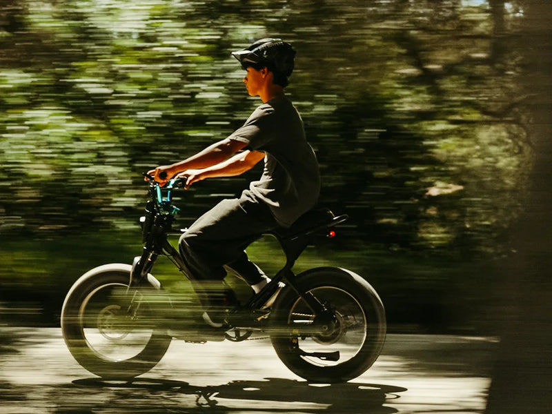 Person riding a Macfox X1S commuter electric bike fast through a forest trail