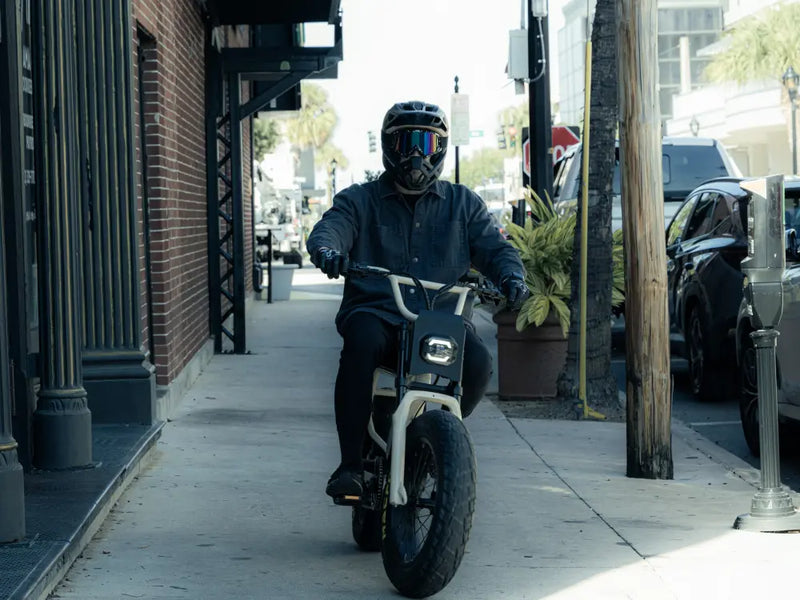 Macfox X7 electric bike being ridden through a narrow urban street