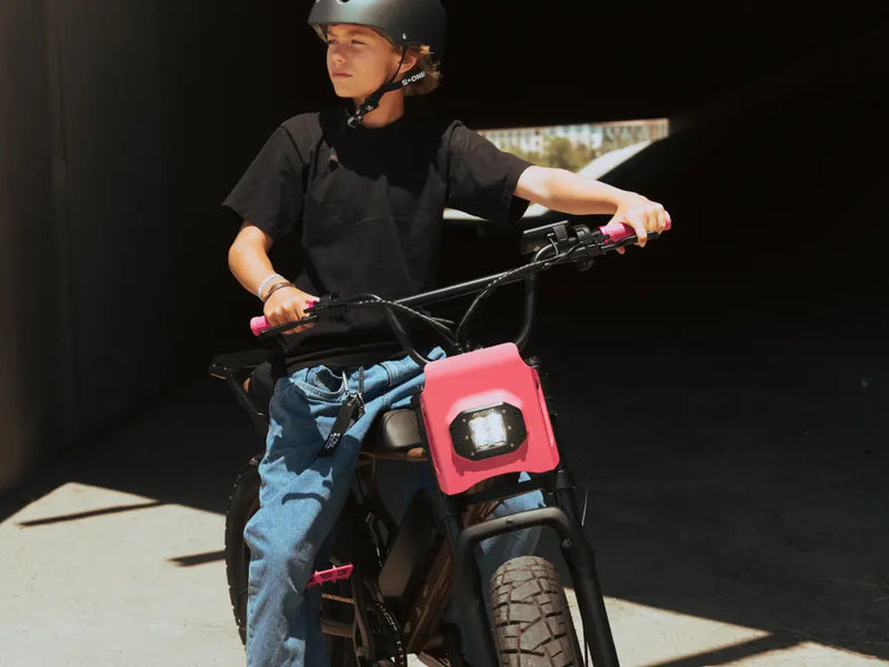 younger rider wearing a helmet sitting on a Macfox X7 electric bike under directional lighting