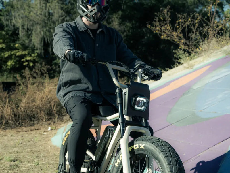 Rider wearing a full-face helmet riding a Macfox X7 fat-tire e-bike on a painted outdoor surface