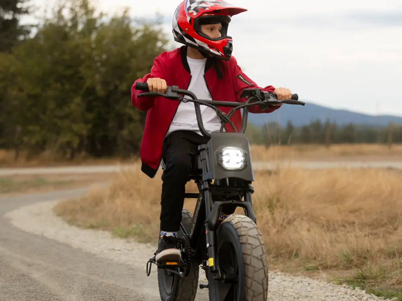 Rider in a red jacket taking a Macfox M16 eBike down a country gravel path