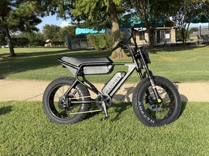 Side view of a Macfox electric bike parked on grass beside a path.
