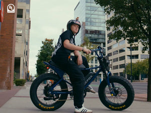 A man riding a Macfox X7 electric bicycle is waiting at a traffic light.