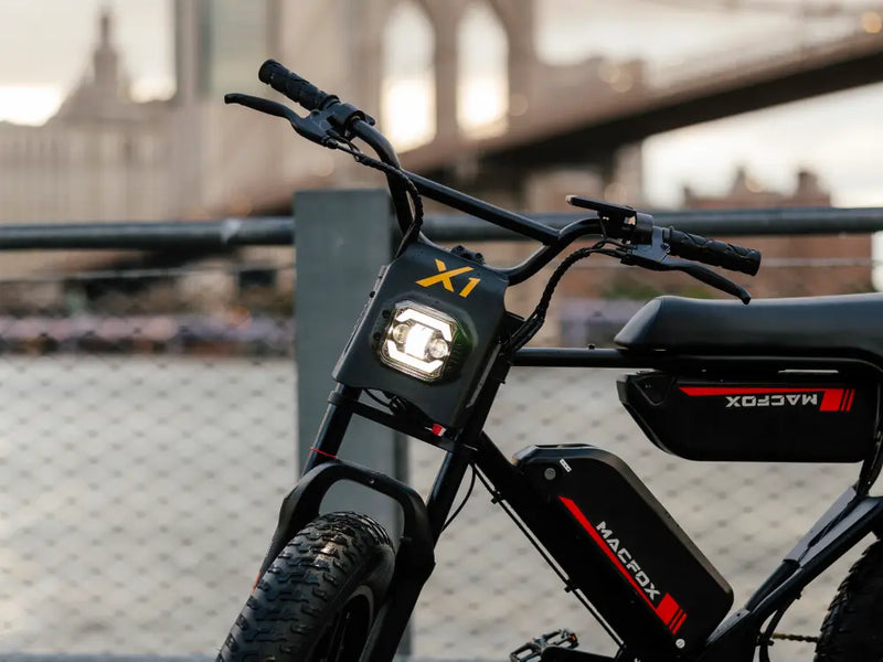 Front view of a Macfox X1S e-bike showing the handlebar setup and riding controls in an urban setting