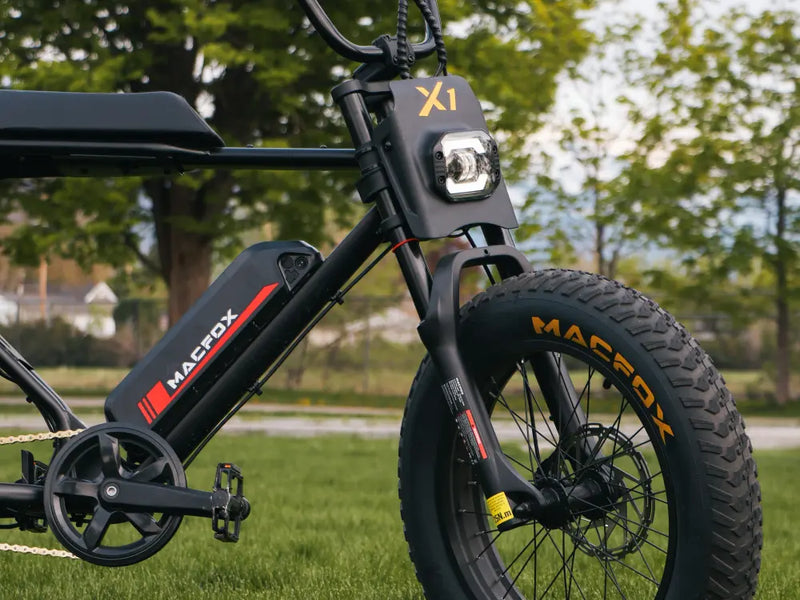Macfox X1S e-bike parked on grass, clearly showing the front wheel, fork, and frame design