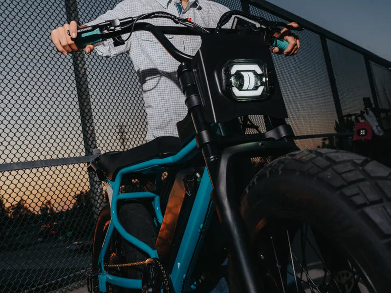 younger rider standing next to a Macfox X7 ebike near a fence at dusk