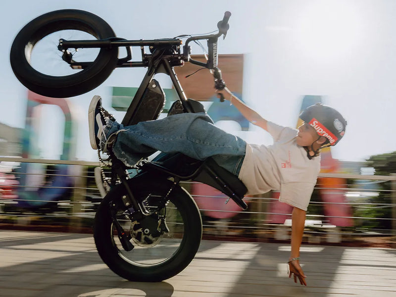 Rider doing a stunt on a Macfox X1S commuter electric bike with one hand touching the ground