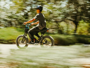 Commuter riding a Macfox X1S eBike at speed along a green outdoor path with motion blur
