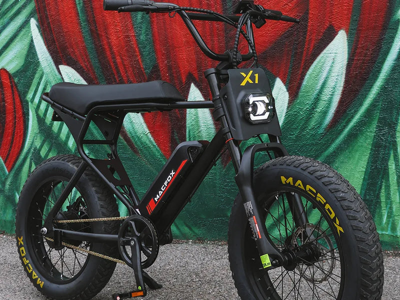 Macfox X1S commuter electric bike parked in front of a colorful graffiti wall