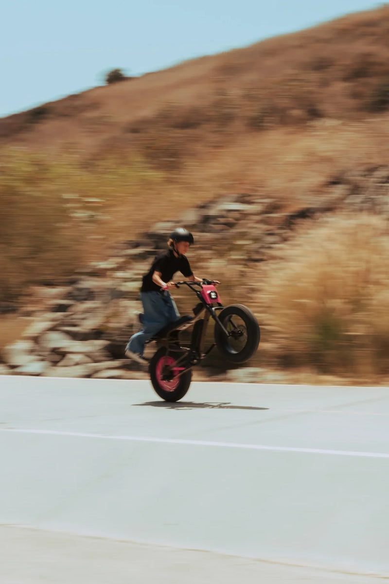 A teenager was driving a modified pink X7 with the front of his bicycle tilted up.