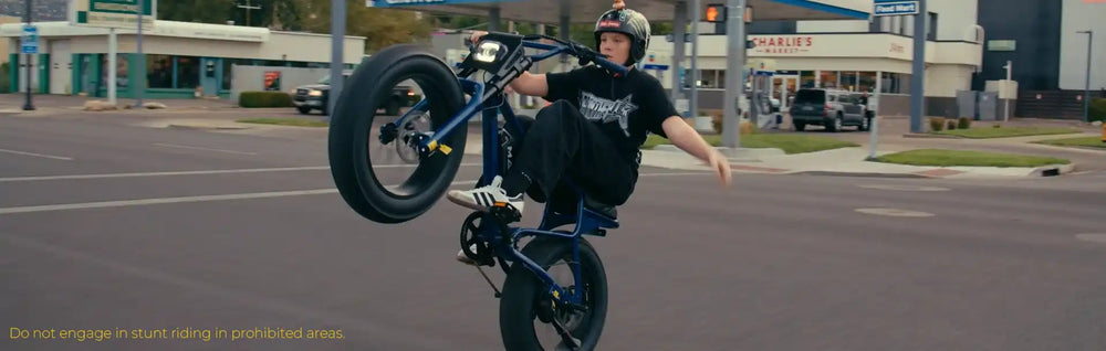 Younger rider performing a wheelie on a Macfox X7 electric bike on a city street